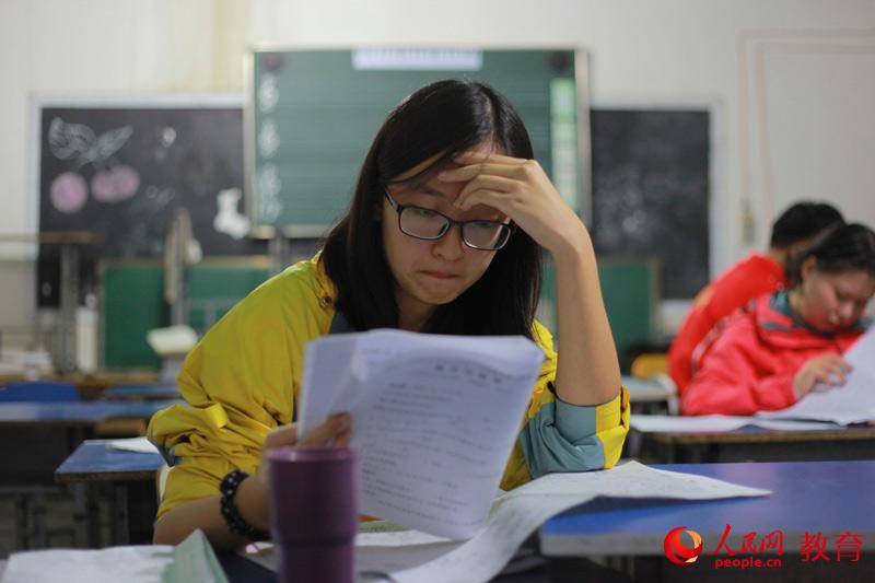 队员陈雨知正仔细检查着批改完的试卷，为第二天的课程做准备。