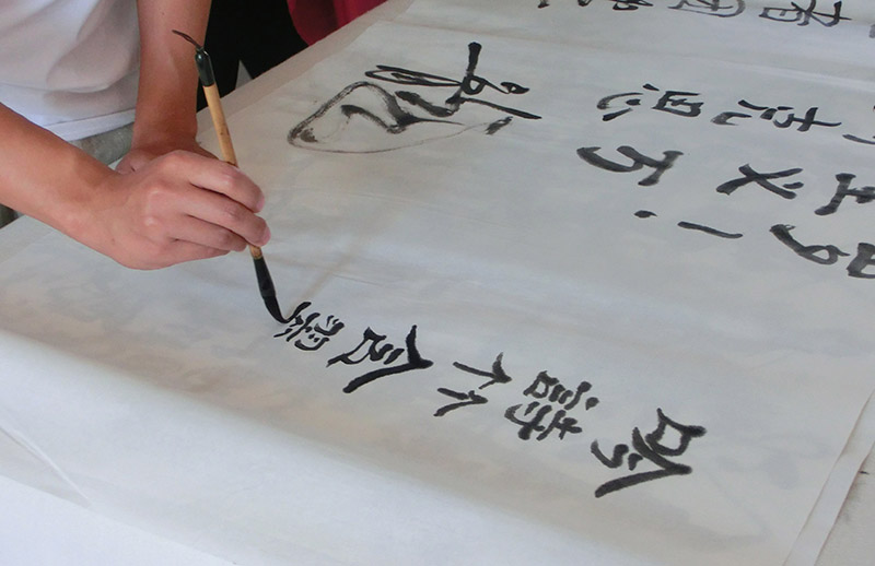 同學們在魯藝美術系教室內的書桌上寫毛筆字。攝影 王玉嬌