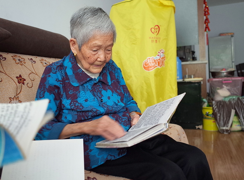89岁老人匡体道在家中翻看笔记本。 