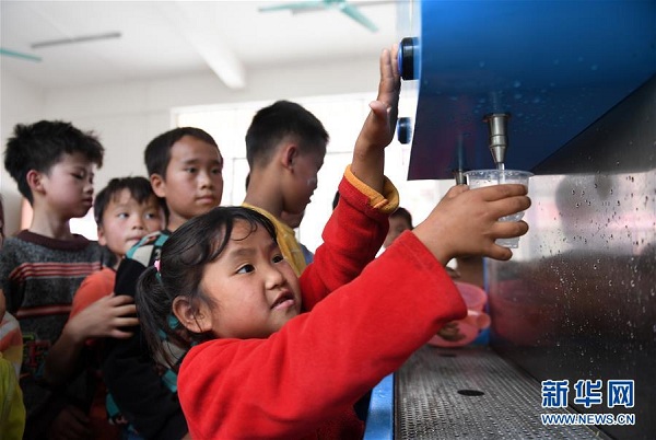 在广西都安瑶族自治县下坳镇隆麻小学，学生在饮水机边接水喝（11月6日摄）。