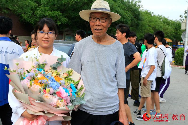老爺爺早早來到考點前等候，第一時間為孫女送上一大束鮮花。李依環 攝