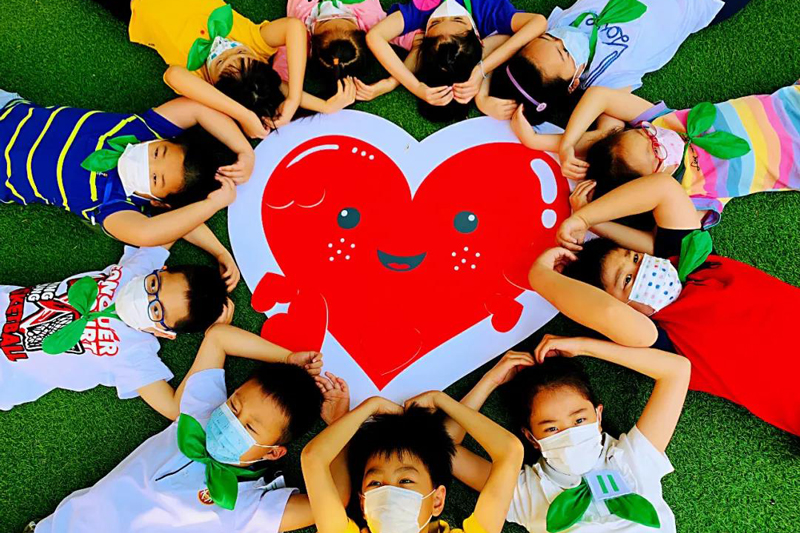 宝山区实验小学学生们围着爱心纸牌，躺成一个圈。（来源：上海教育微信公众号）