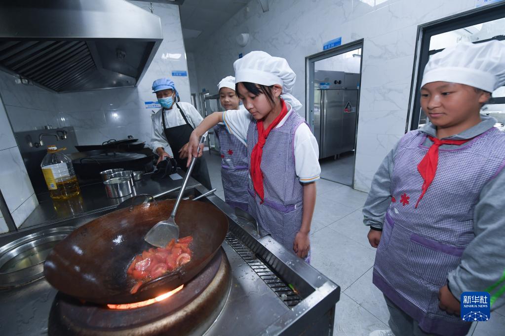 5月12日，东林镇第二小学的学生在劳动实践课上学习切菜和烹饪。