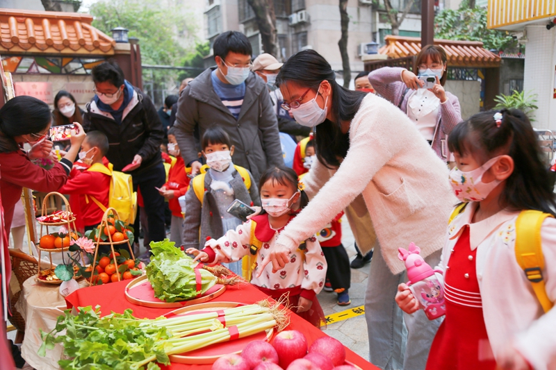 2月6日，廣州市番禺區北城幼兒園的家長向孩子講解開學摸生菜寓意“生生猛猛”的嶺南民俗。北城幼兒園供圖