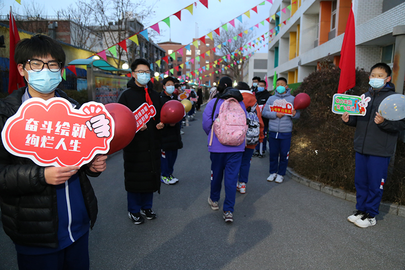 2月13日，北京市第十一中學，校園禮儀學生分列學校甬路兩側，手舉印有勵志標語的手牌，歡迎同學們回到校園。北京市第十一中學供圖