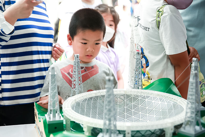 儿童在“中国天眼科学工坊”展区观察天眼模型了解中国制造的大国重器。中国儿童中心供图