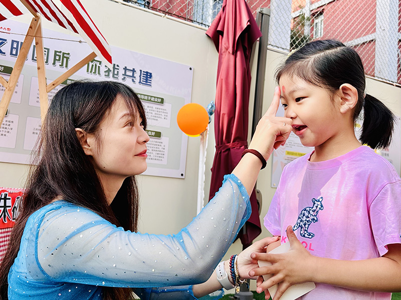 9月1日，北京市朝陽區勁鬆第一幼兒園舉辦了主題為“太陽花的世界——向陽花開，初秋相見”的開學典禮。老師們設計制作了歡迎小朋友的展板、漂亮的氣球拱門，讓孩子們走過“快樂門”“健康門”“成長門”，希望孩子們在新學期能夠快樂健康成長。圖為老師在小朋友的額頭點朱砂。北京市朝陽區教委供圖