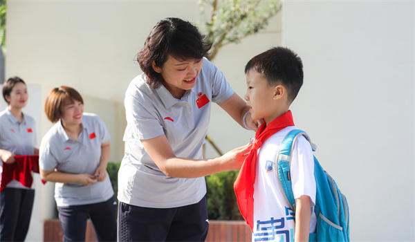 8月30日，雄安史家胡同小學學生體驗學校生活。老師為學生佩戴校徽。