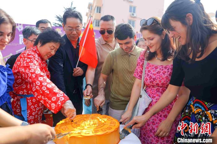 海外留学生与当地居民一同分切“月饼”蛋糕。张鹰 摄