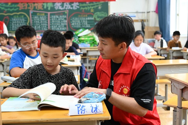 郑州市二七区暑托班的志愿者提醒孩子写功课。东说念主民网记者王玉兴摄