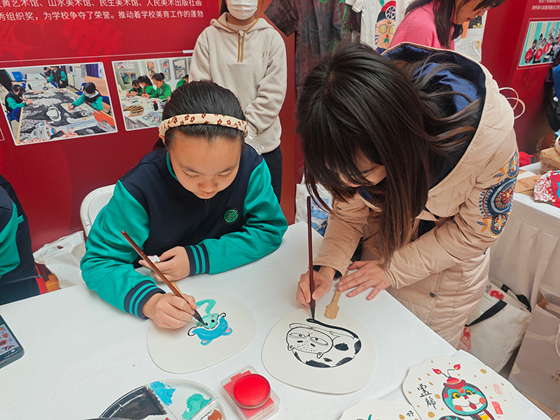 展示活动上，学生和老师一起画扇面。人民网记者 郝孟佳摄