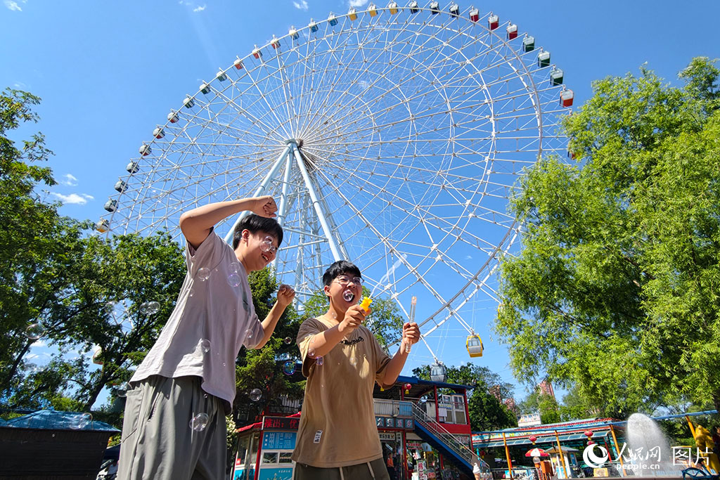 2026年5月30日，在遼寧沈陽萬泉公園，孩子們正在88米高的摩天輪下快樂地玩耍。人民網記者 周頌雪攝