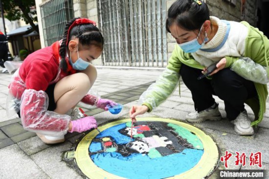 小学生正在社区彩绘井盖。　陈超 摄