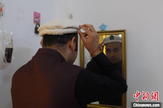 图为一名巴基斯坦留学生正在对着镜子整理自己的传统帽饰。　刘俊聪 摄