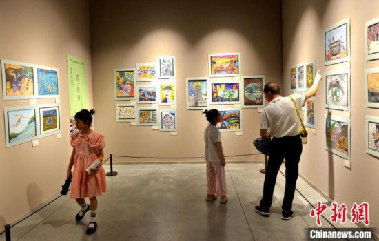 图为家长带着孩子参观展览。　吕明 摄