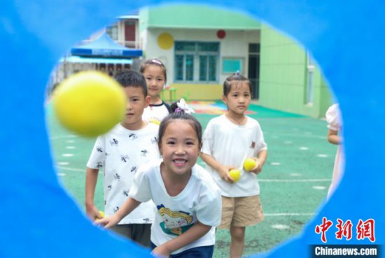 在肥西縣山南鎮中心幼兒園，孩子們在玩布洞投球游戲。　陳家樂 攝