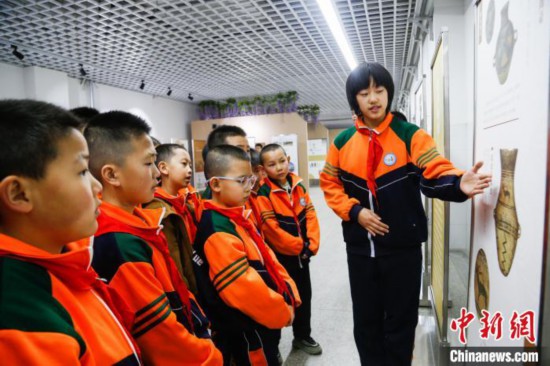 图为学生通过展板了解出土于青海省海东市乐都区的辛店文化文物鹿纹彩陶瓮。中新社记者 马铭言 摄