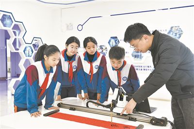 在山东日照金海岸小学，老师指导学生练习机械臂毛笔书写编程。新华社记者 郭绪雷摄