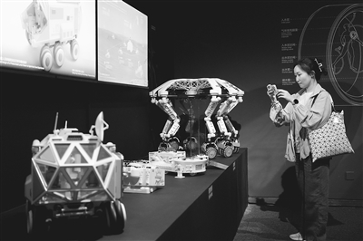 图为观众观看“宇宙考古：时空探索”展览上展示的月面多功能平台及智能火星探测器模型。本报记者 洪星摄