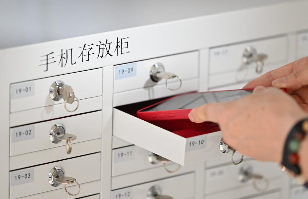6月16日，在天津大学评卷点，工作人员将手机放入存放柜中。新华社记者 李然 摄